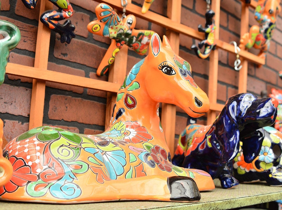 A row of colorful ceramic figurines on a shelf.