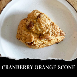 A scone on a white plate, labeled "Cranberry Orange Scone.